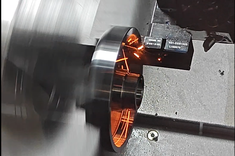 Proces toczenia na tokarce CNC, widoczne iskrzenie oraz obracające się wrzeciono,